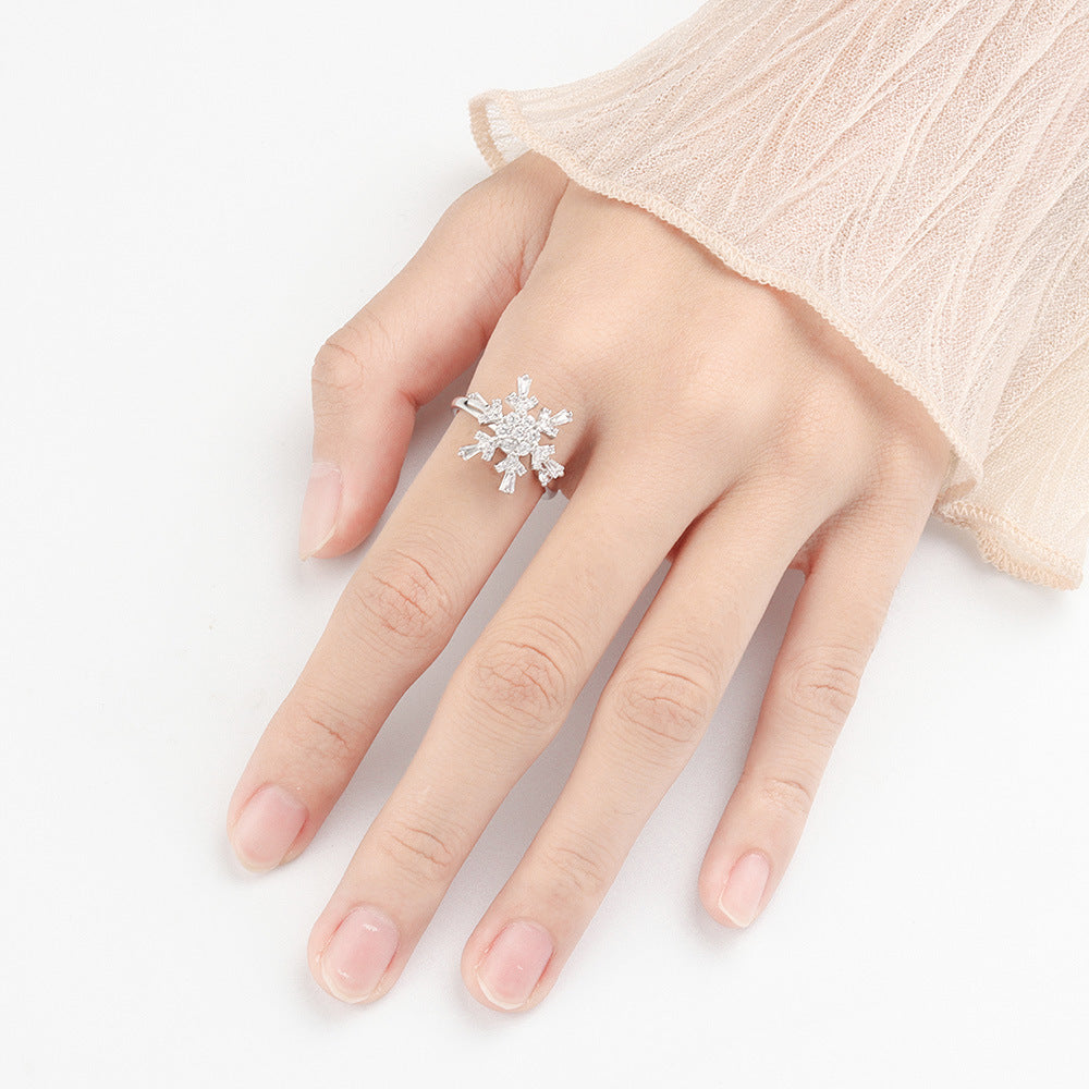 Women's S925 sterling silver spinning snowflake ring with CZ diamonds on a woman's hand with soft beige sleeve, available at Lumē; buy high-quality anti-anxiety fidget jewelry